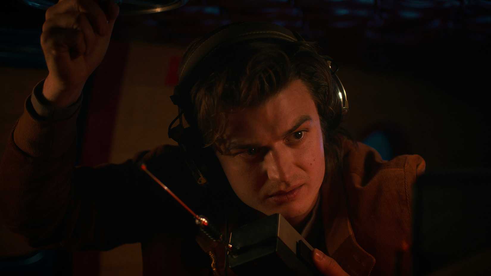 Steve in the dark with headphones talking on a radio in Stranger Things.