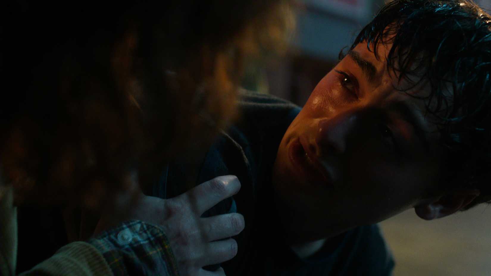 Will on the ground terrified as Joyce comforts him in Stranger Things.