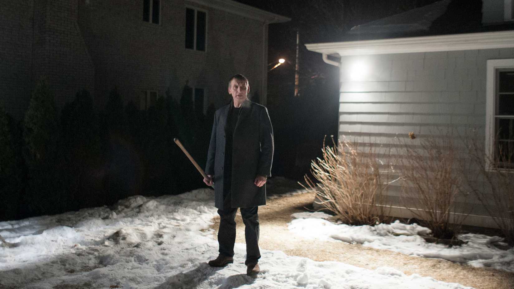 Matt standing in the snow, holding a large stick and looking around, in The Leftovers.