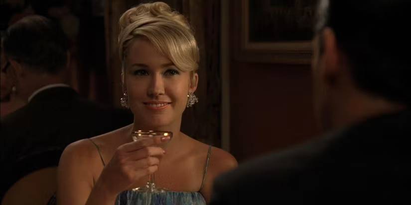 Bethany holding a glass while talking to Don over dinner in Mad Men.