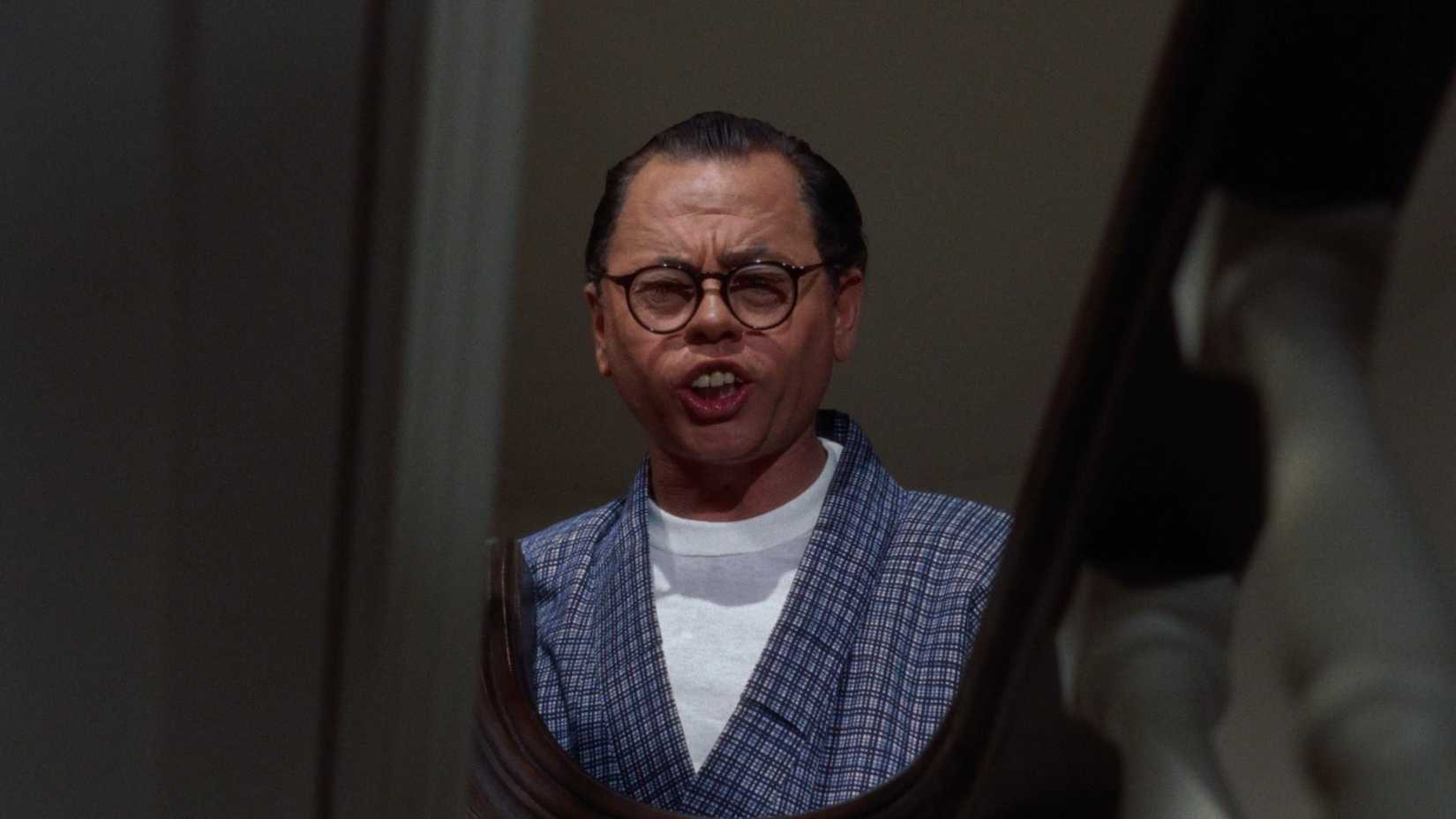 Mr. Yunioshi stands in a stairwell in Breakfast at Tiffany's
