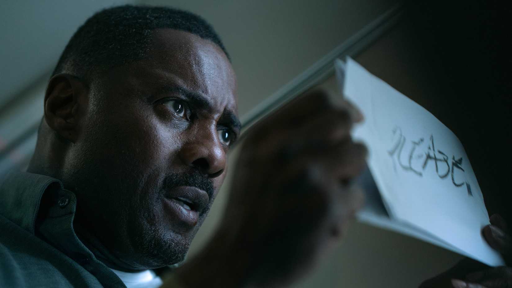 Idris Elba's Sam Nelson holding a piece of paper in Hijack