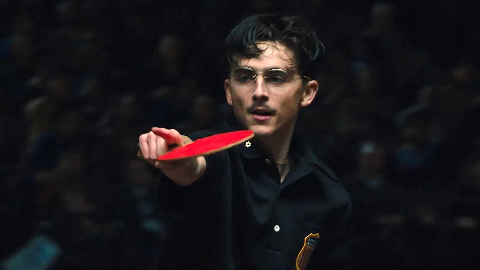 Timothée Chalamet holding a ping pong bat as Marty Mauser in Marty Supreme