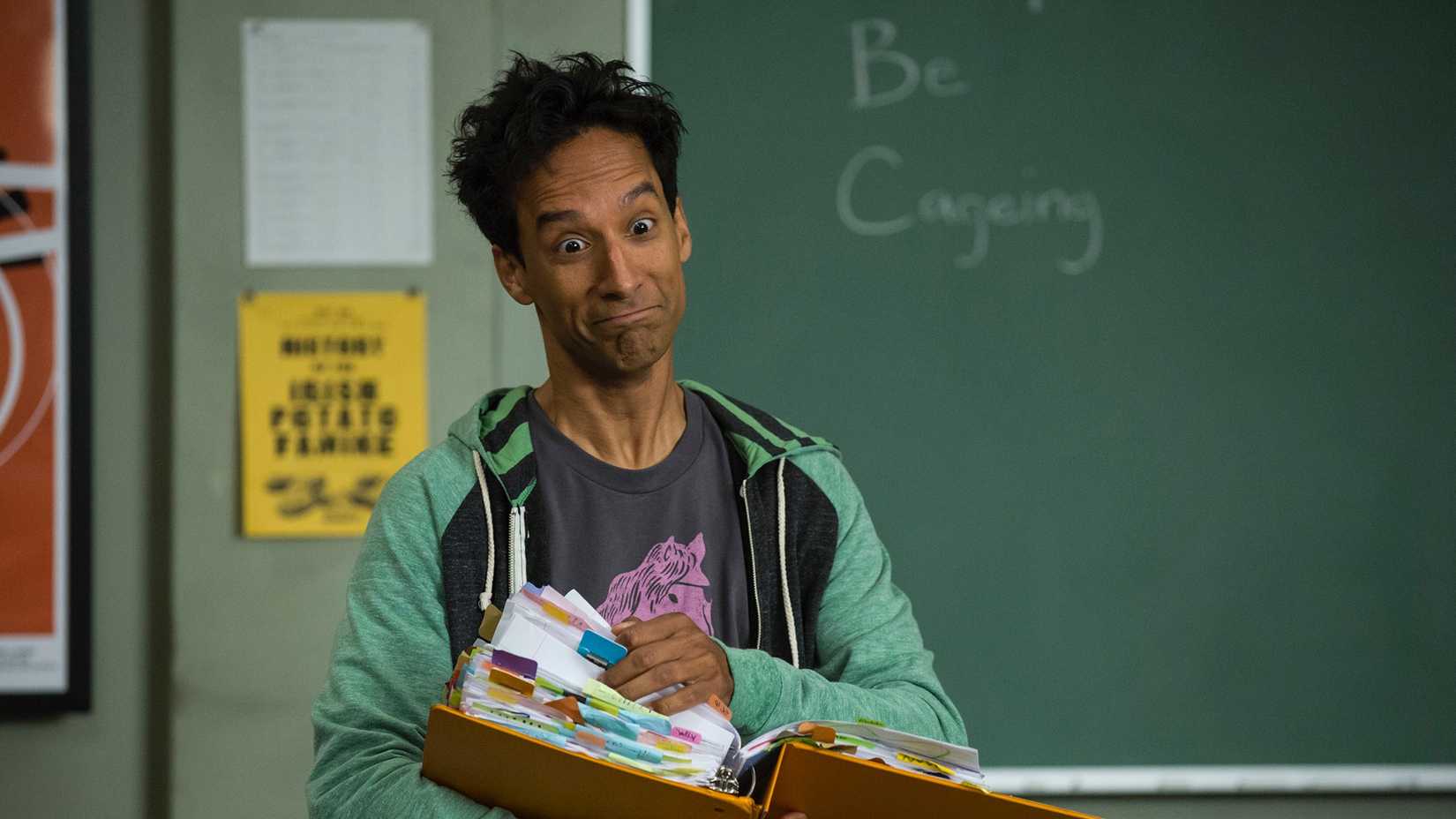 Abed looking dishevelled as he stands at the front of the class with a large binder in Community.