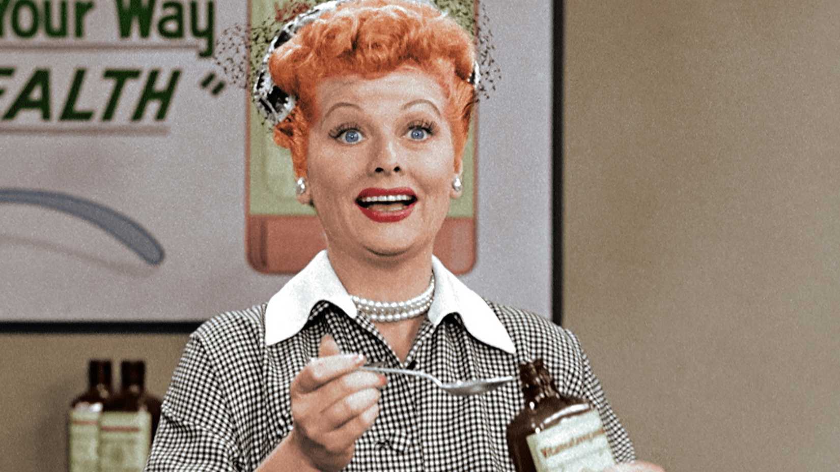 Lucy Ricardo smiling while holding a bottle and spoon in I Love Lucy.