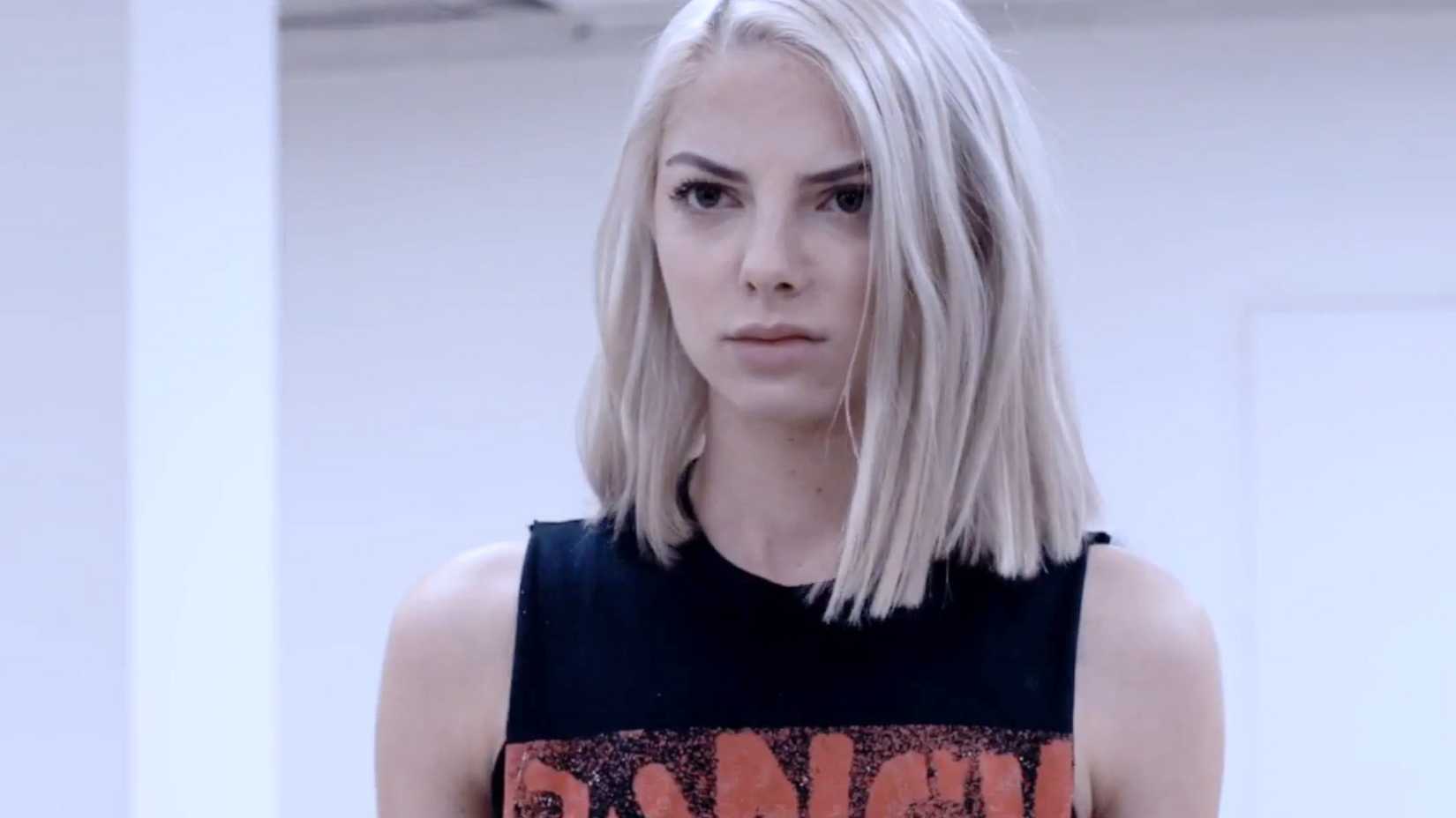 A young blonde woman standing in a tank top on a white background in Maximum Ride.