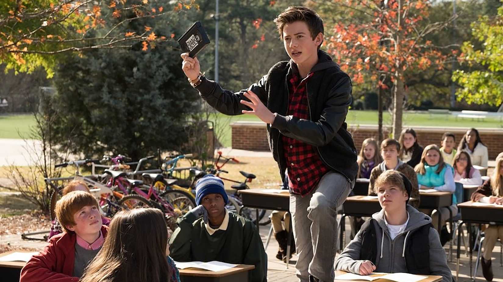 A young boy stands atop his desk as other kids look on in Middle School: The Worst Year of My Life.