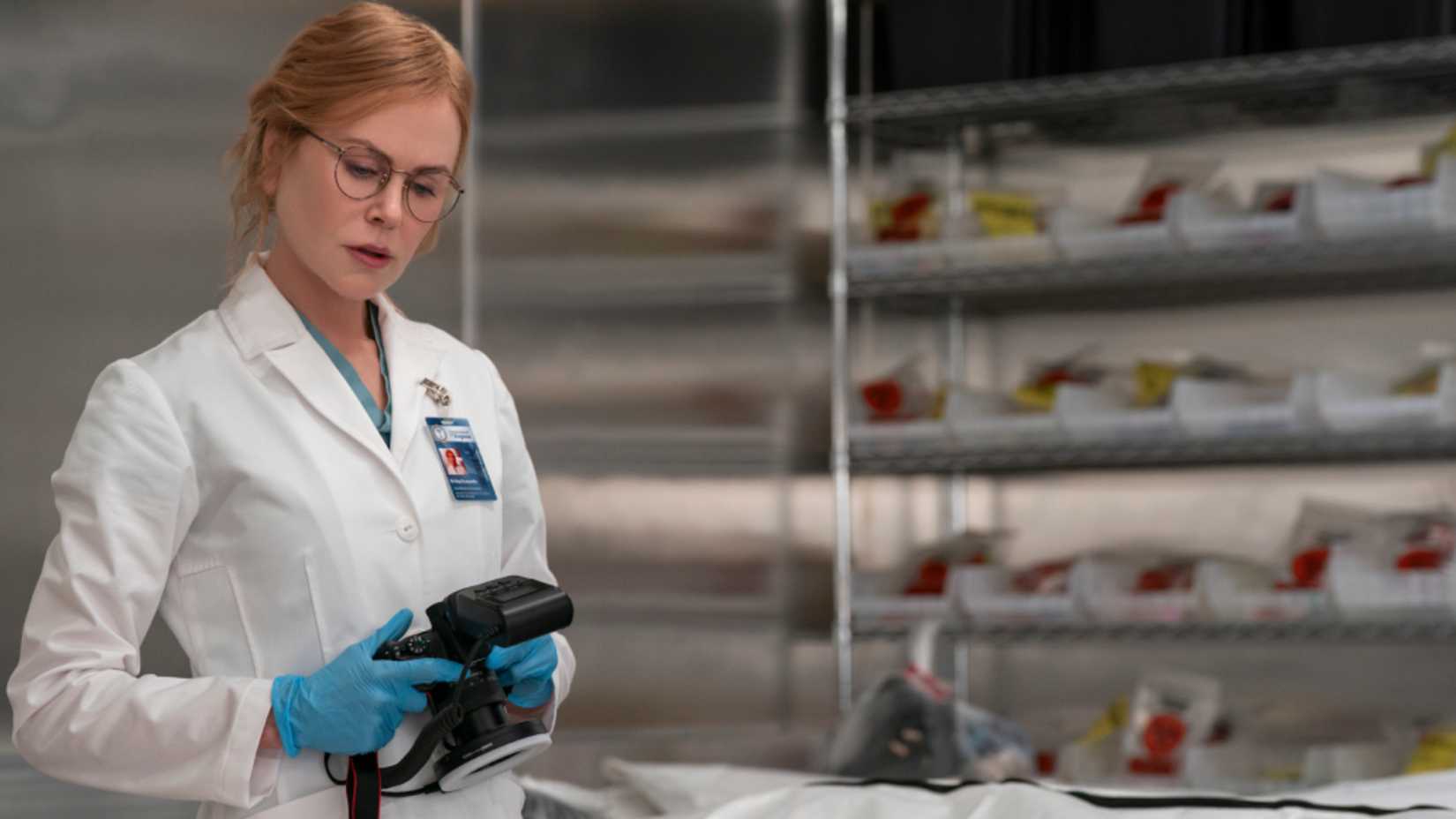 Kay holds a camera in a lab coat in Scarpetta