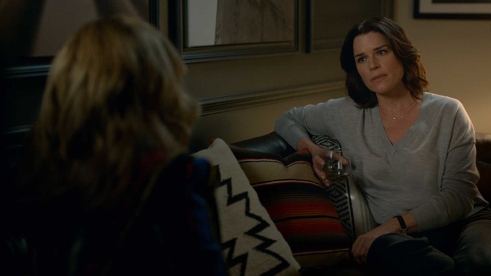 Maggie drinking wine on the couch talking to Lorna in The Lincoln Lawyer.