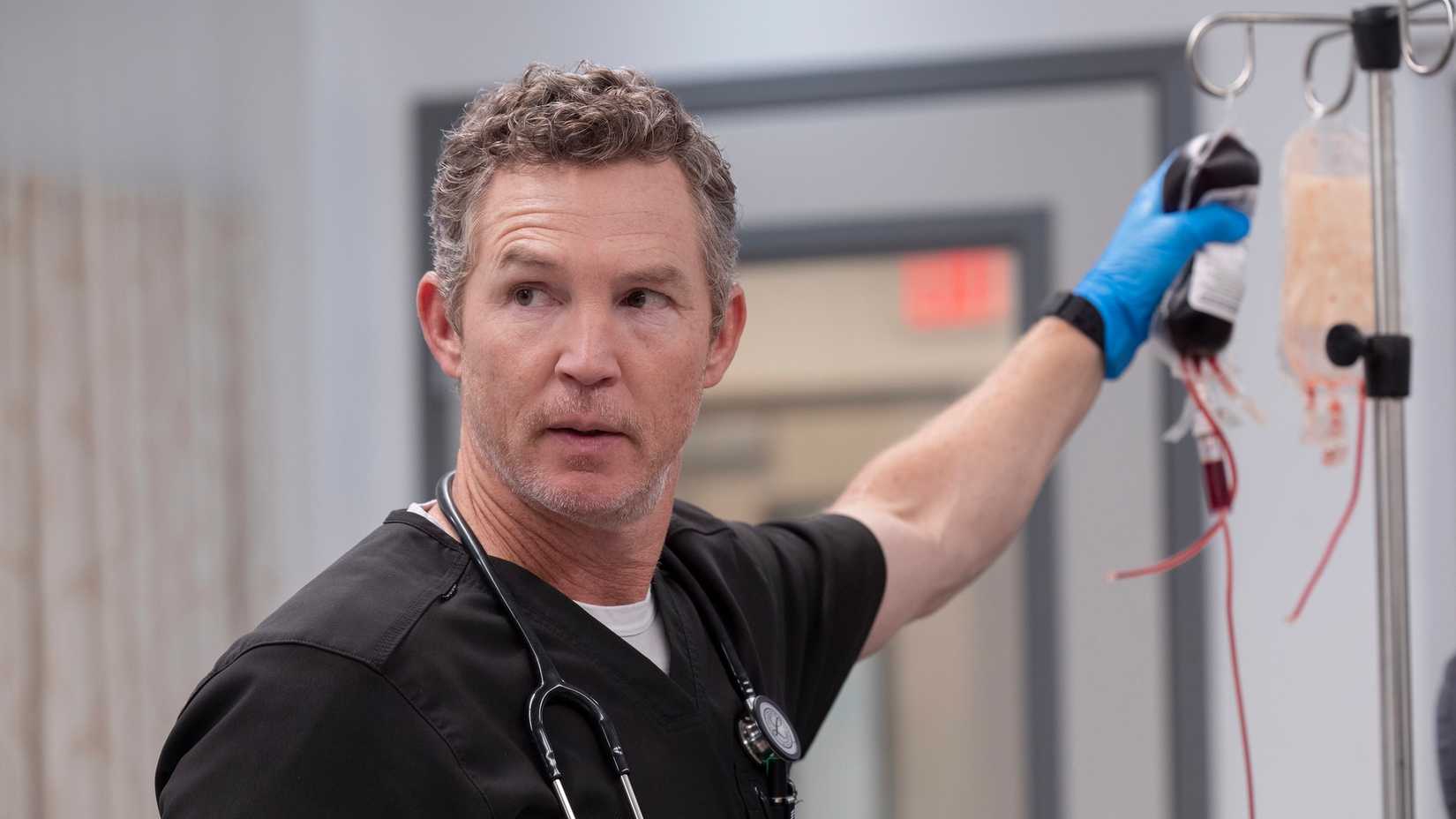 Dr. Abbot holding onto a bag of fluid and looking back in The Pitt.