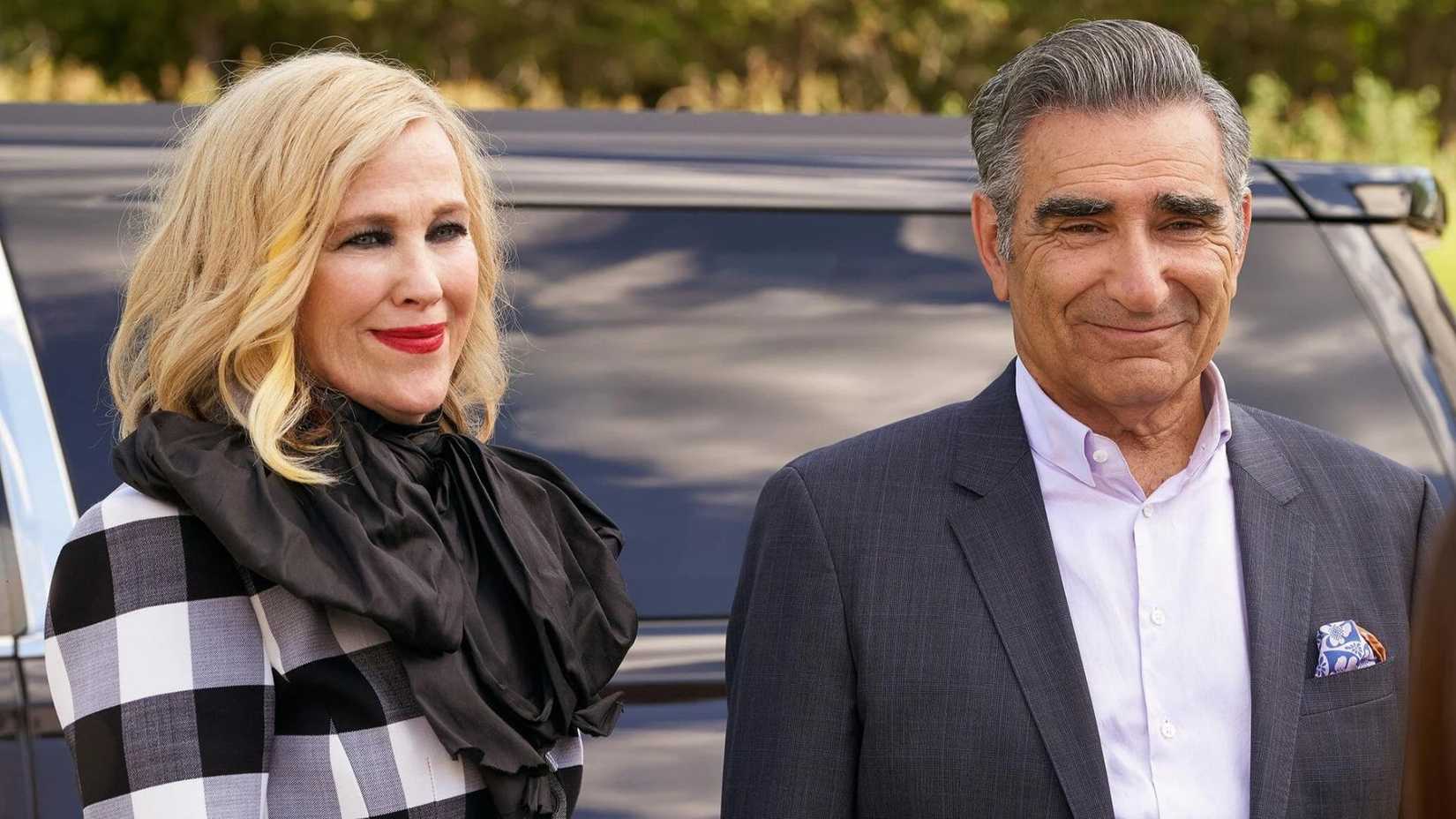 Catherine O'Hara as Moira and Eugene Levy as Johnny standing in front of a car in Schitt's Creek.