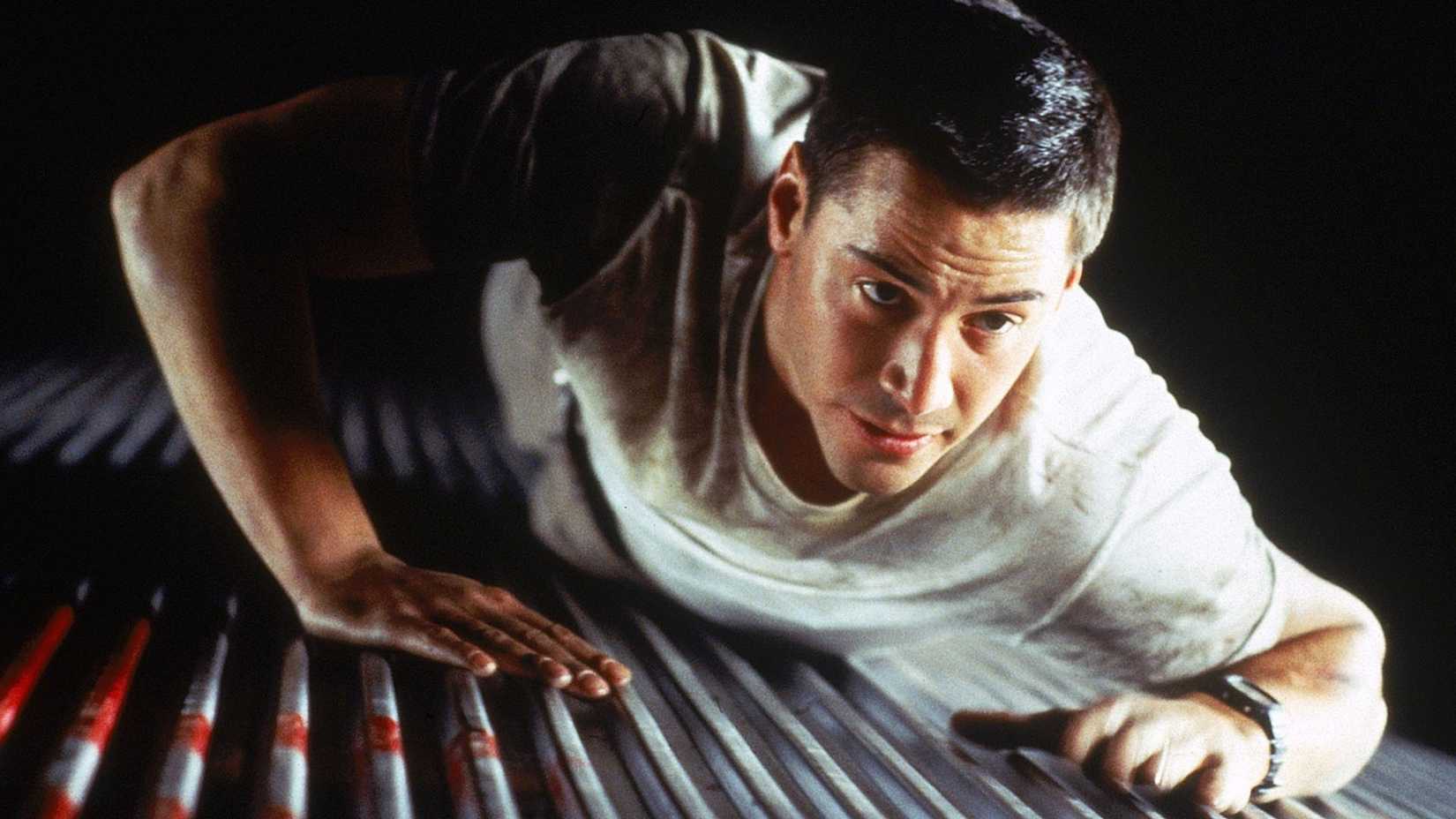 Keanu Reeves crawls on the top of a train in Speed