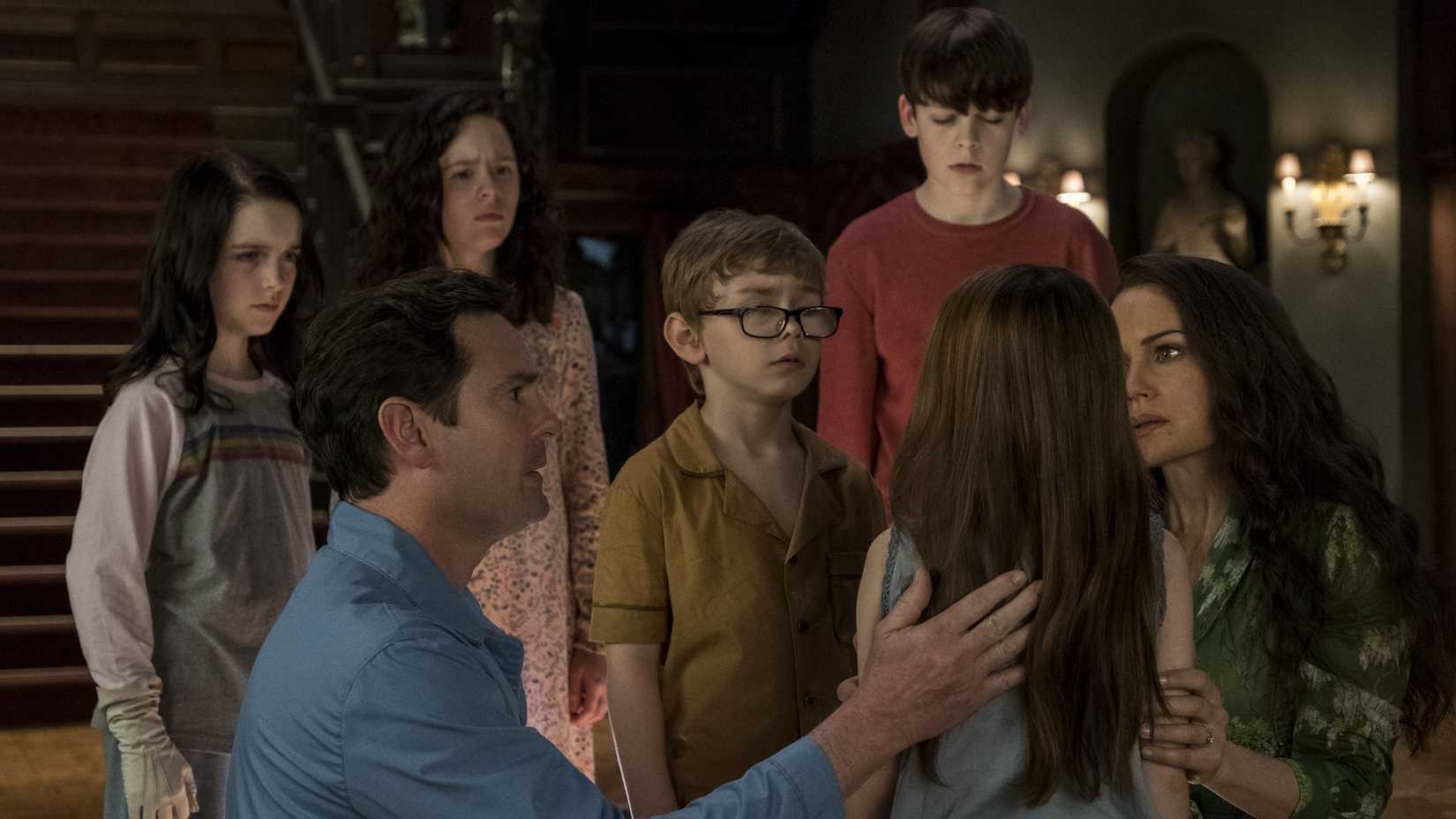 The Crain family looking concerned as they gather around Nell in The Haunting of Hill House.