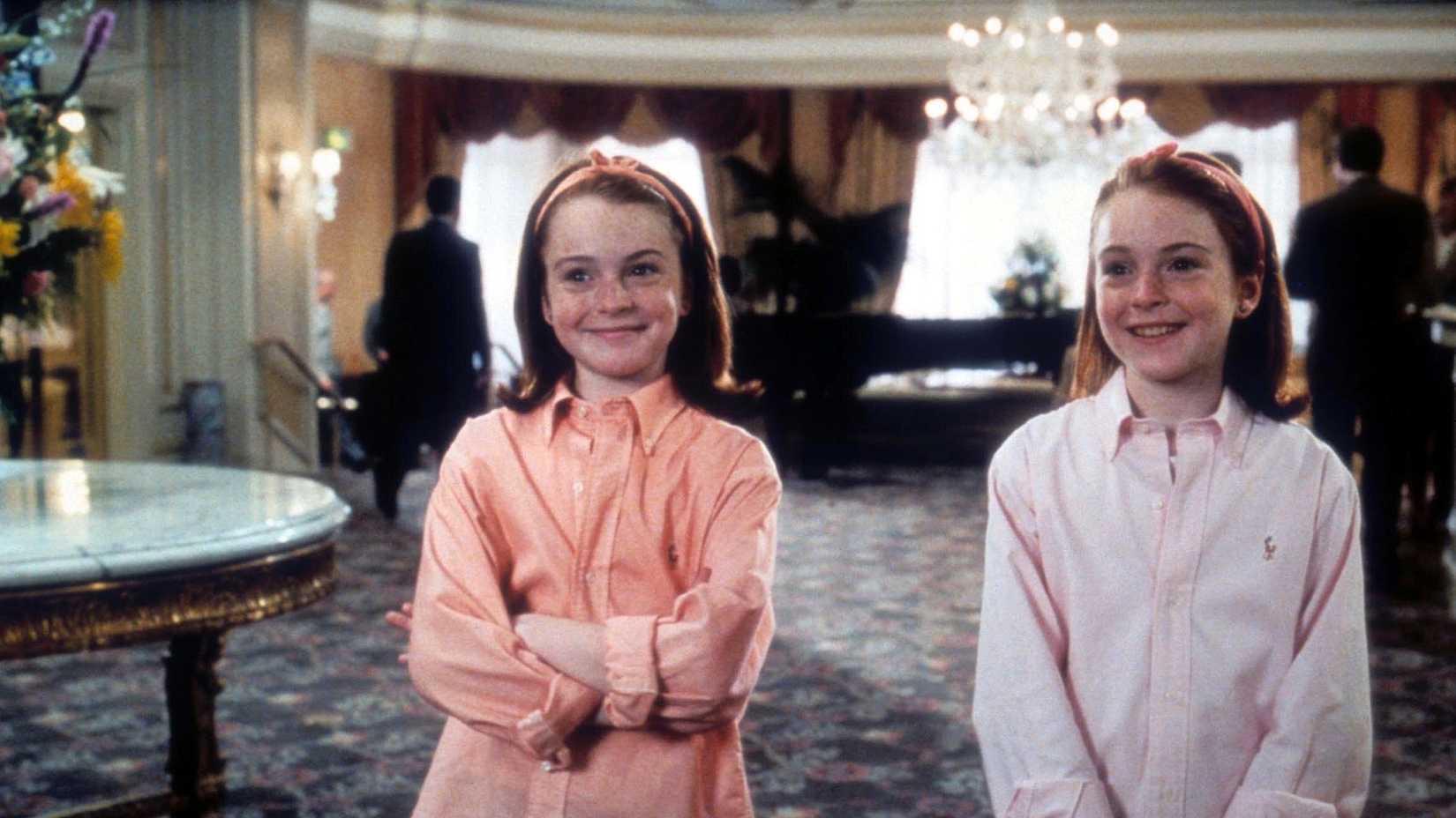 Lindsay Lohan as Hallie and Annie smiling as they stand in the hotel lobby in The Parent Trap.