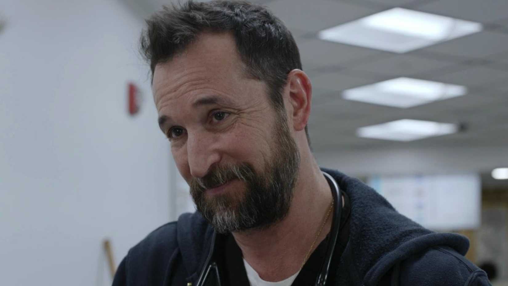 Robby (Noah Wyle) smiling at someone off-screen in The Pitt.