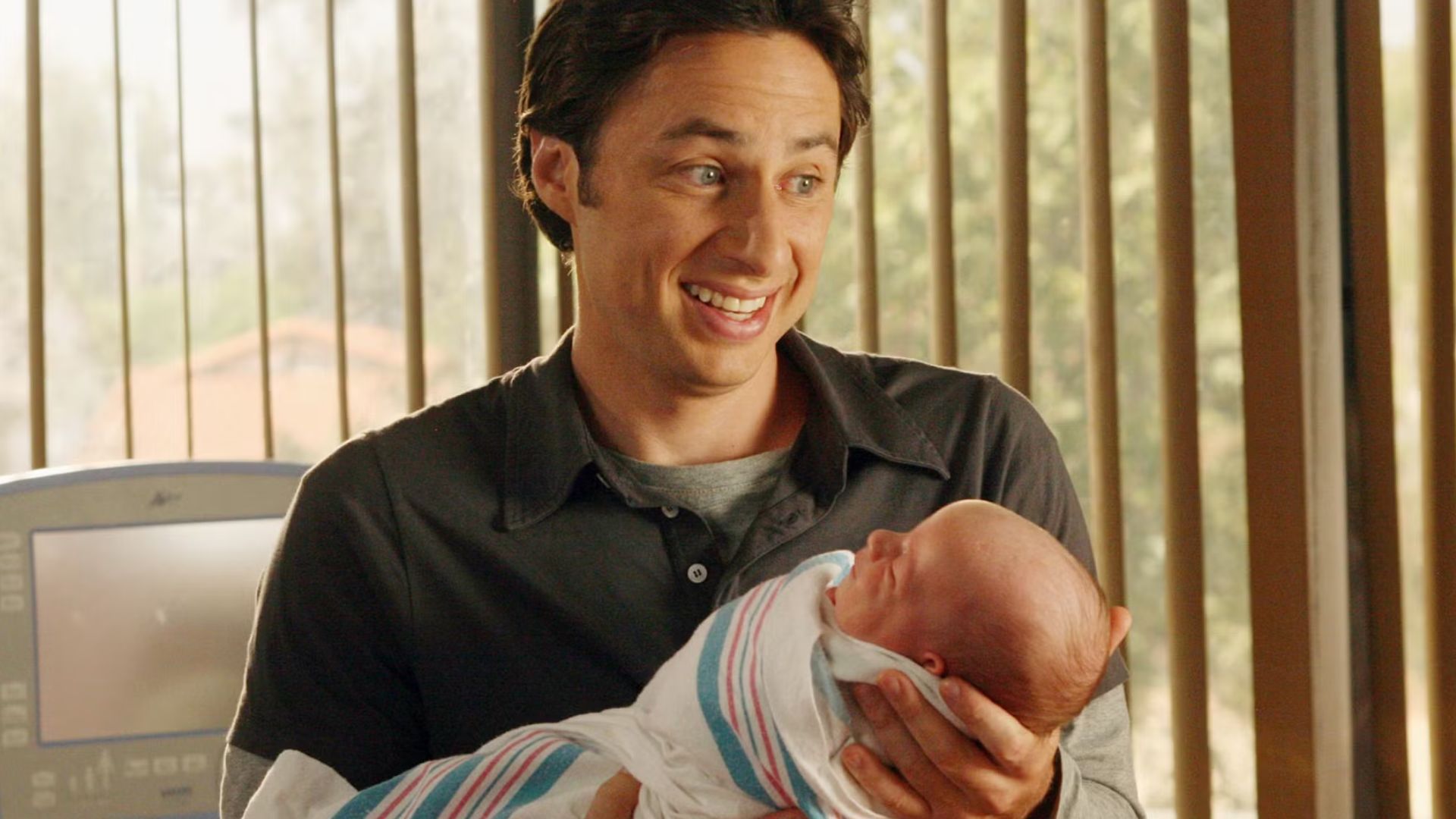 jd smiling as he holds sam in scrubs