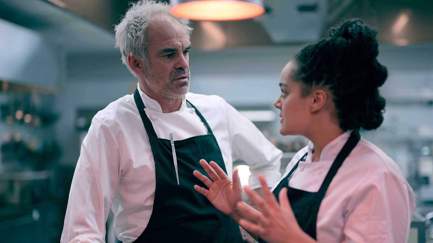 Nick and Camille talking in the kitchen intensely in Boiling Point.