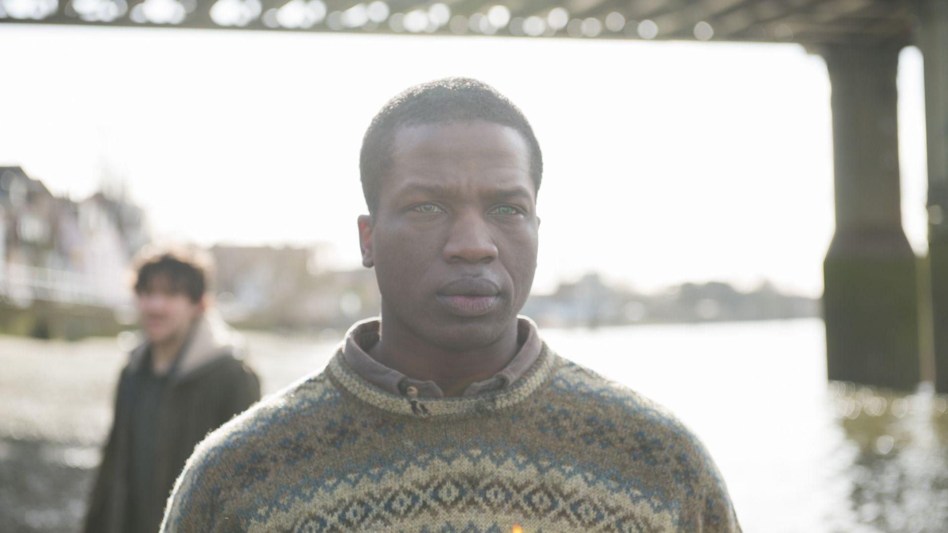 Sope Dirisu as Fred, standing underneath a nearby bridge and staring ahead, in Humans.