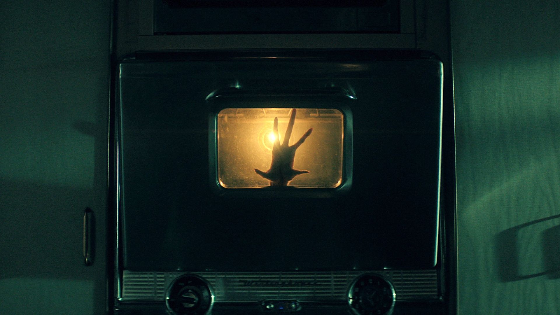 An alien hand pressed against the glass of a kitchen oven in The Boroughs