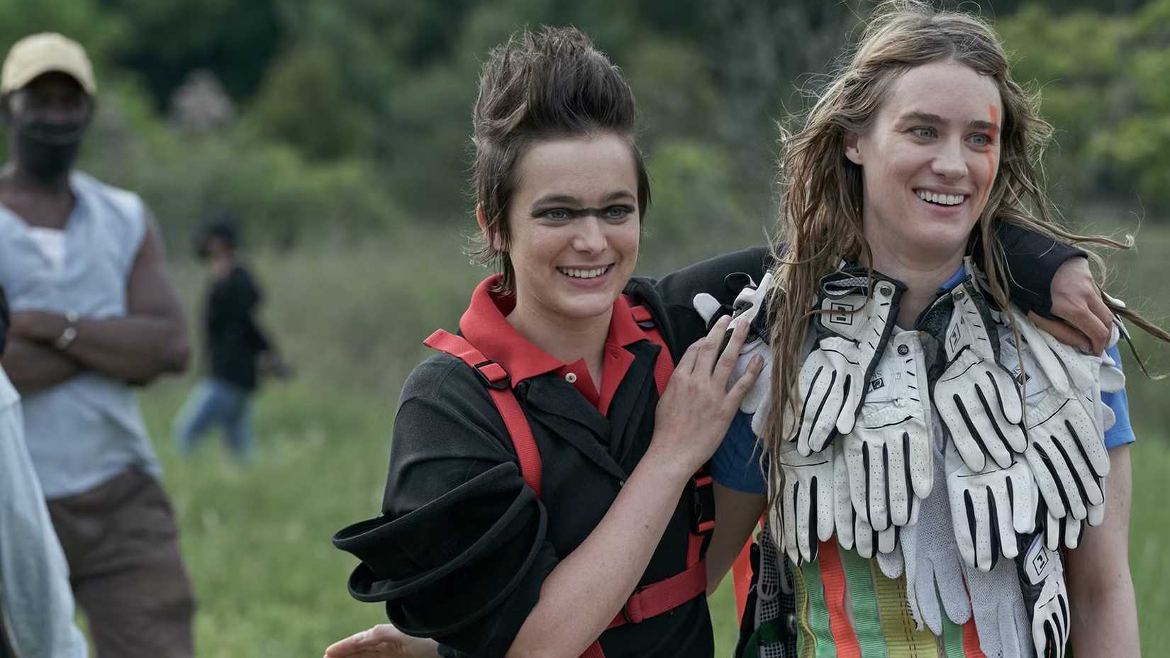 Kirsten and Alexandra, dressed up in costumes, walking together and smiling in Station Eleven.