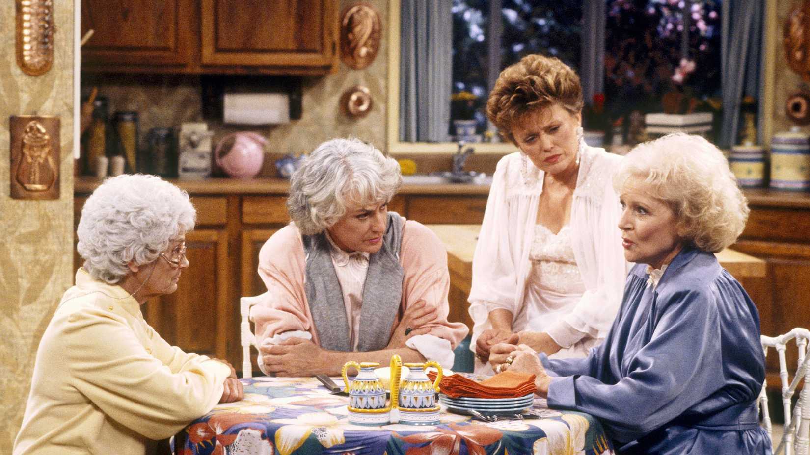 Rose, Blanche, Sophia, and Dorothy talking around a kitchen table in The Golden Girls.