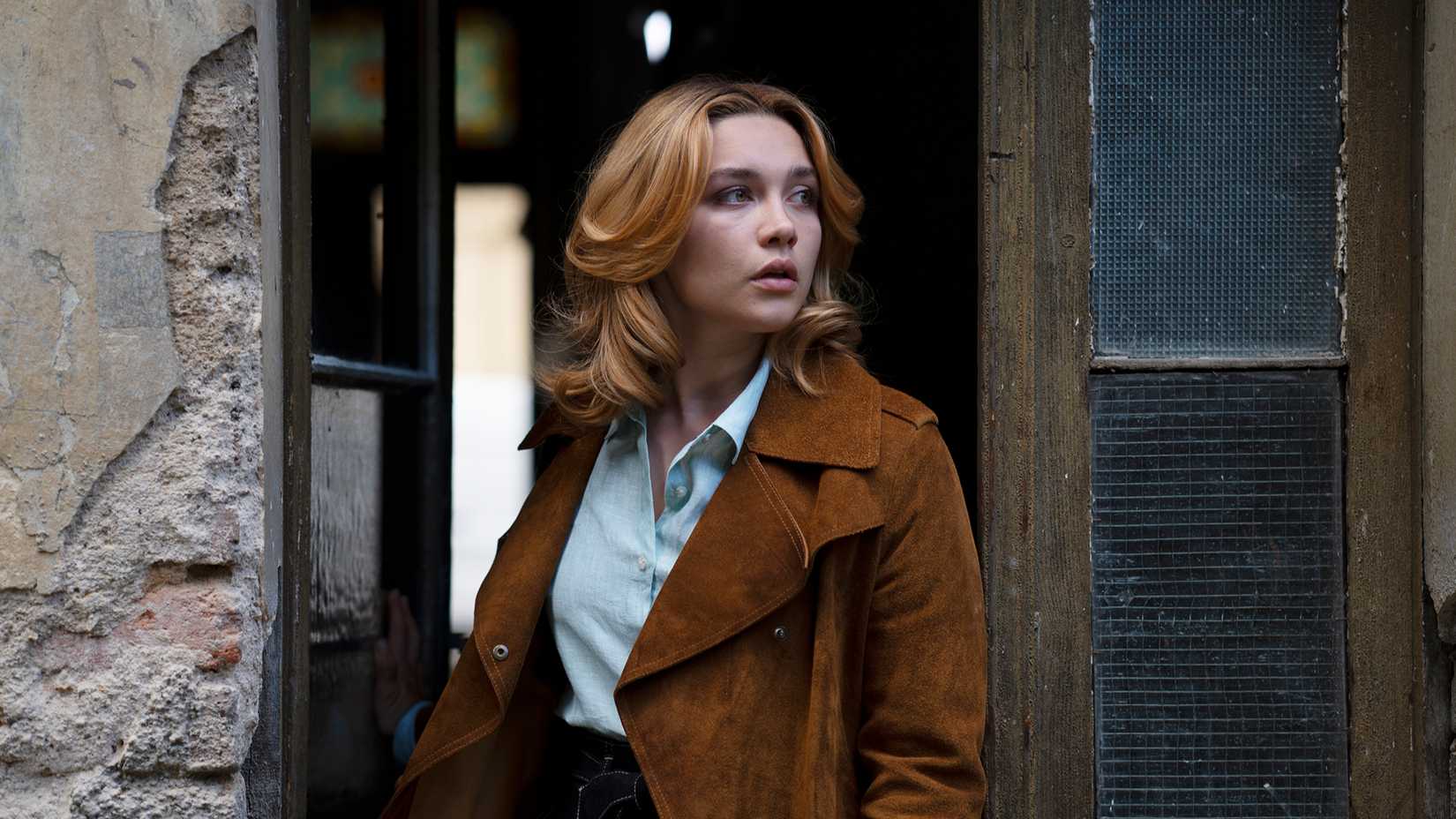Florence Pugh as Charlie Ross leaning out of a doorway in The Little Drummer Girl.