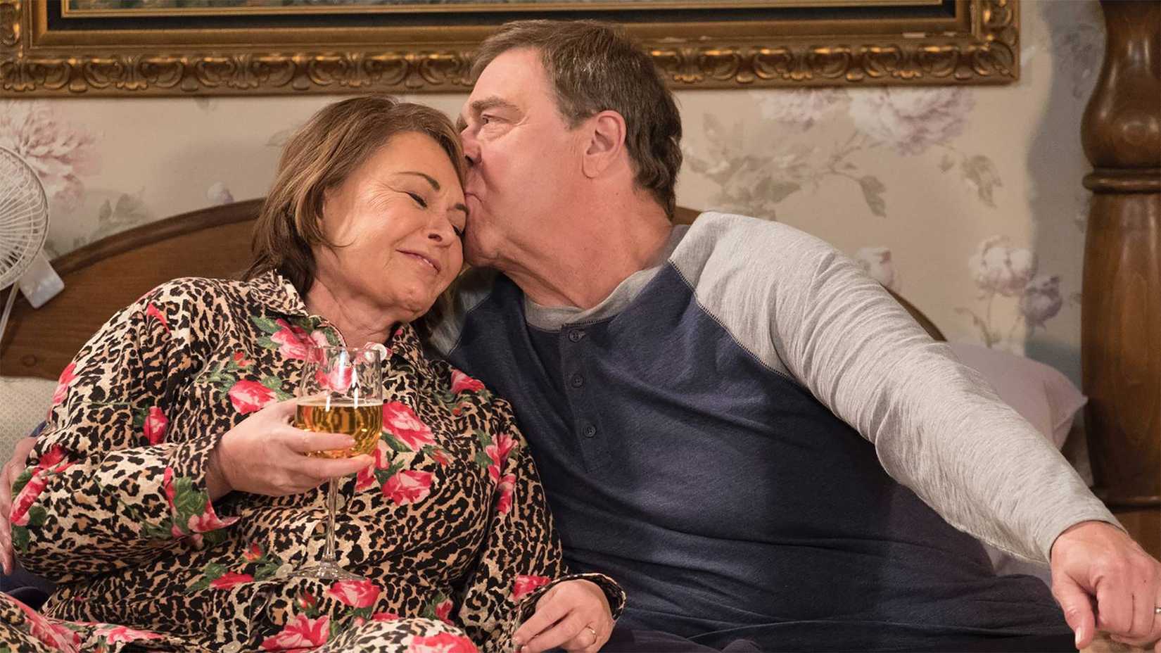 Roseanne and Dan on the couch together, her drinking wine in Roseanne.