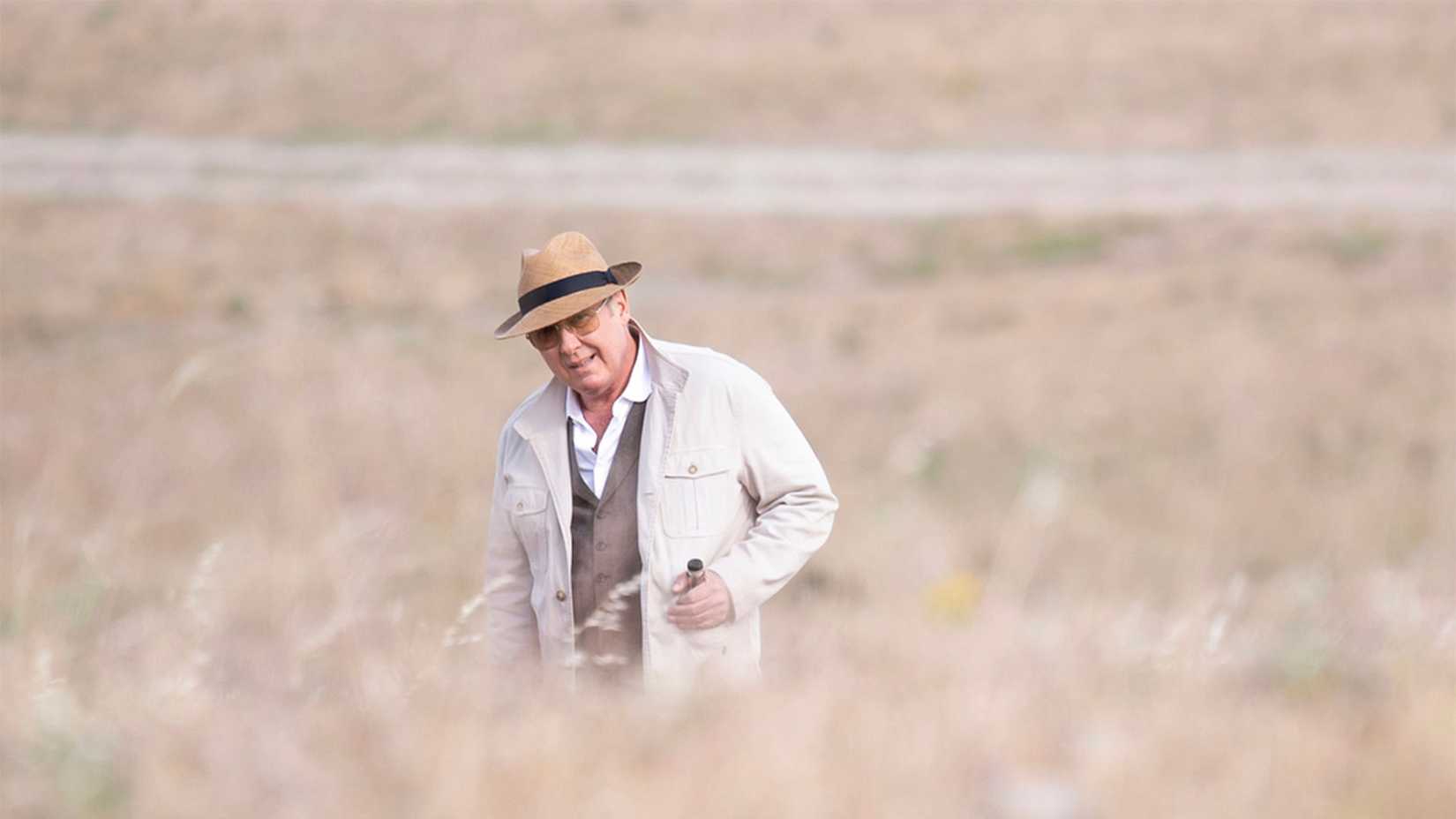 Red walking through a field of hay in The Blacklist.