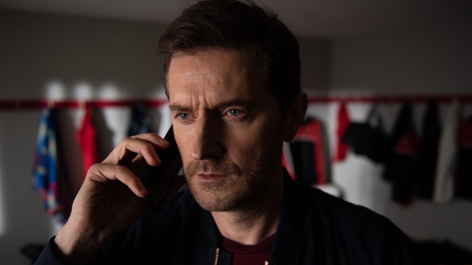 Adam holds a phone to his ear in The Stranger