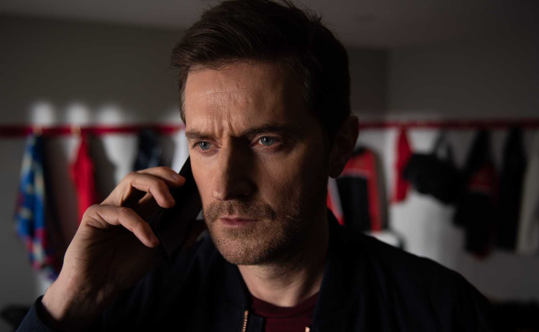 Adam holds a phone to his ear in The Stranger