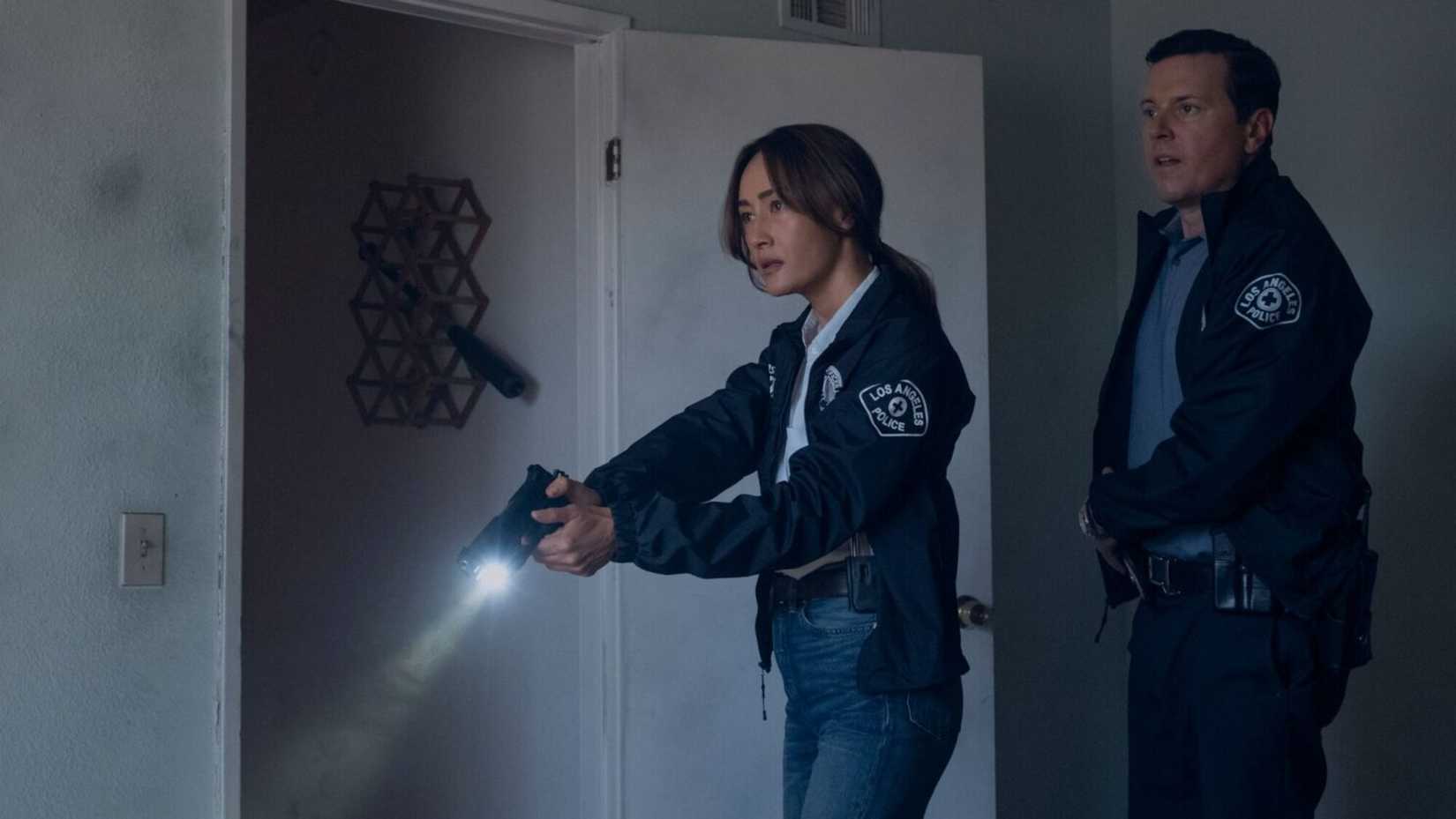 Ballard holds a gun and flashlight in Ballard