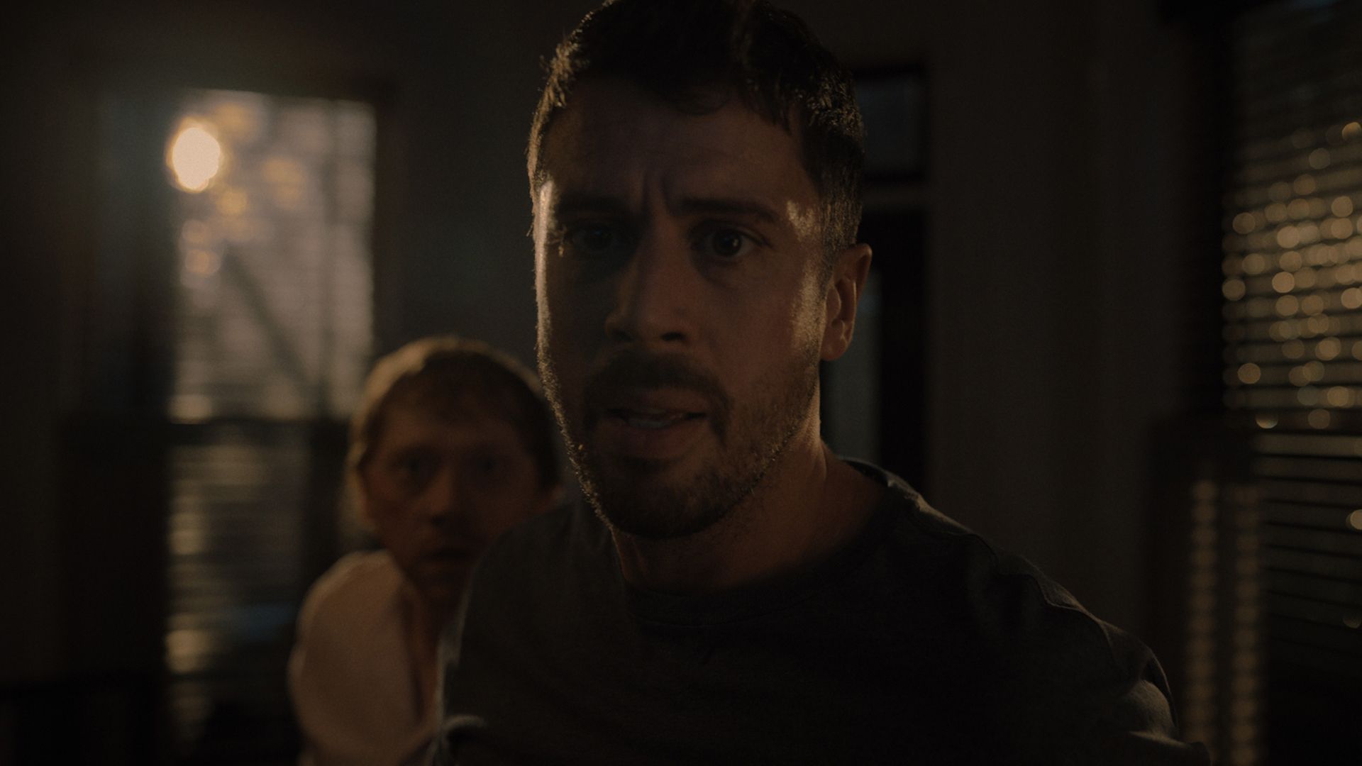 A close-up of Toby looking terrified, Julian behind him in Servant.