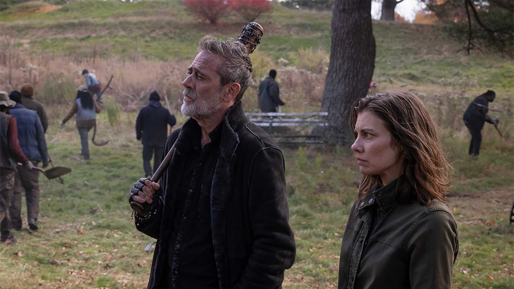 Maggie and Negan walking in a field as people work around them in The Walking Dead: Dead City.