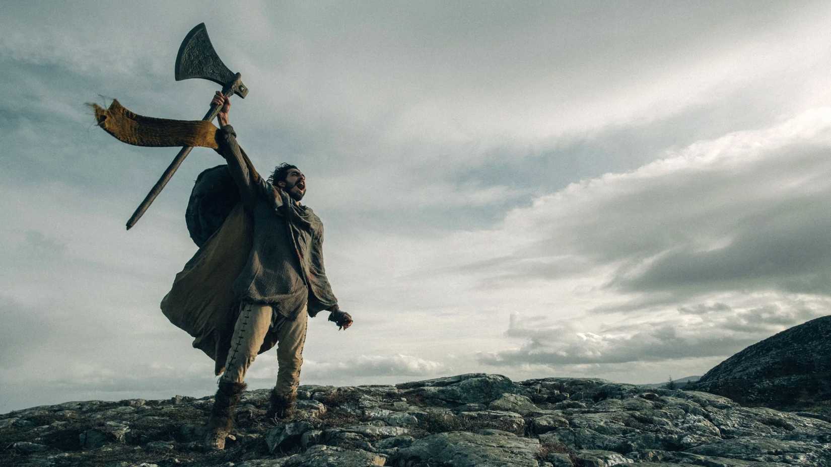 Dev Patel cheering with an ax in 'The Green Knight'