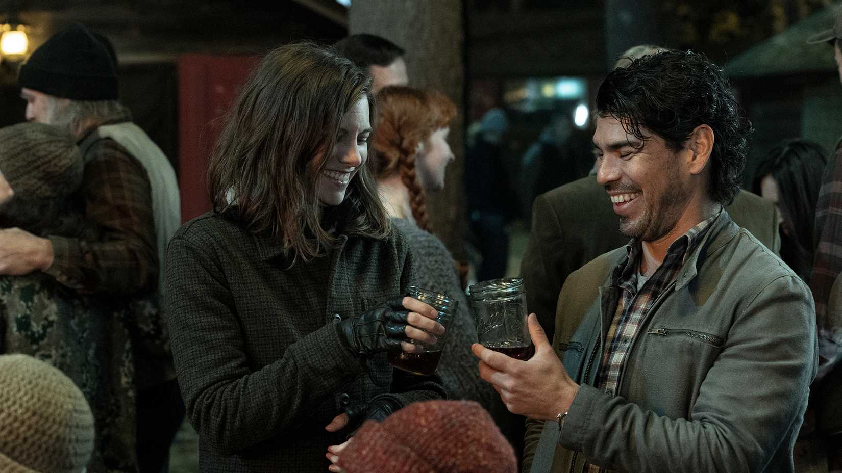 Maggie and Luis clinking glasses and laughing at a party in The Walking Dead: Dead City.