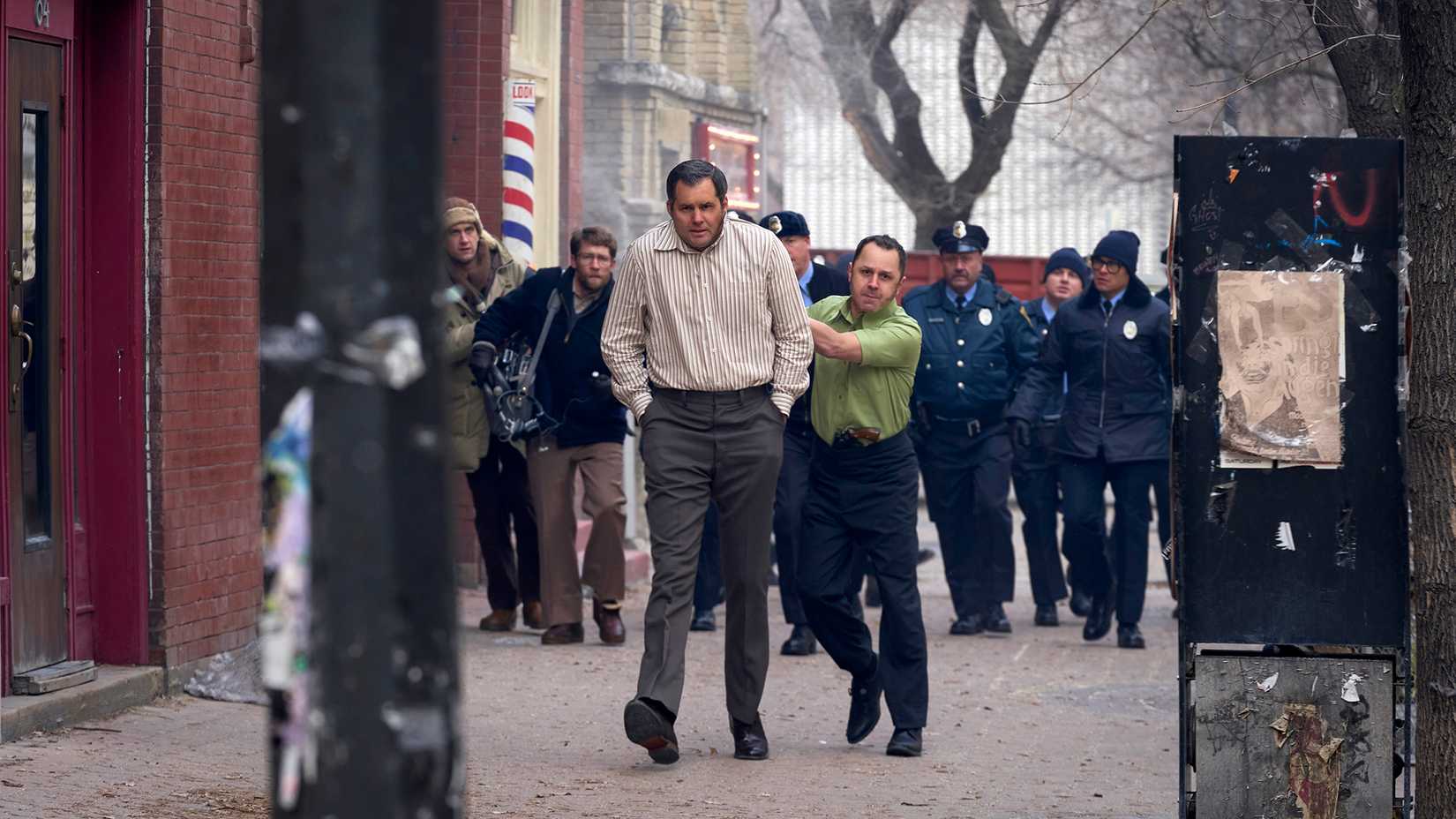 Tony leading Dick through the streets with a gun to his back in American Hostage.