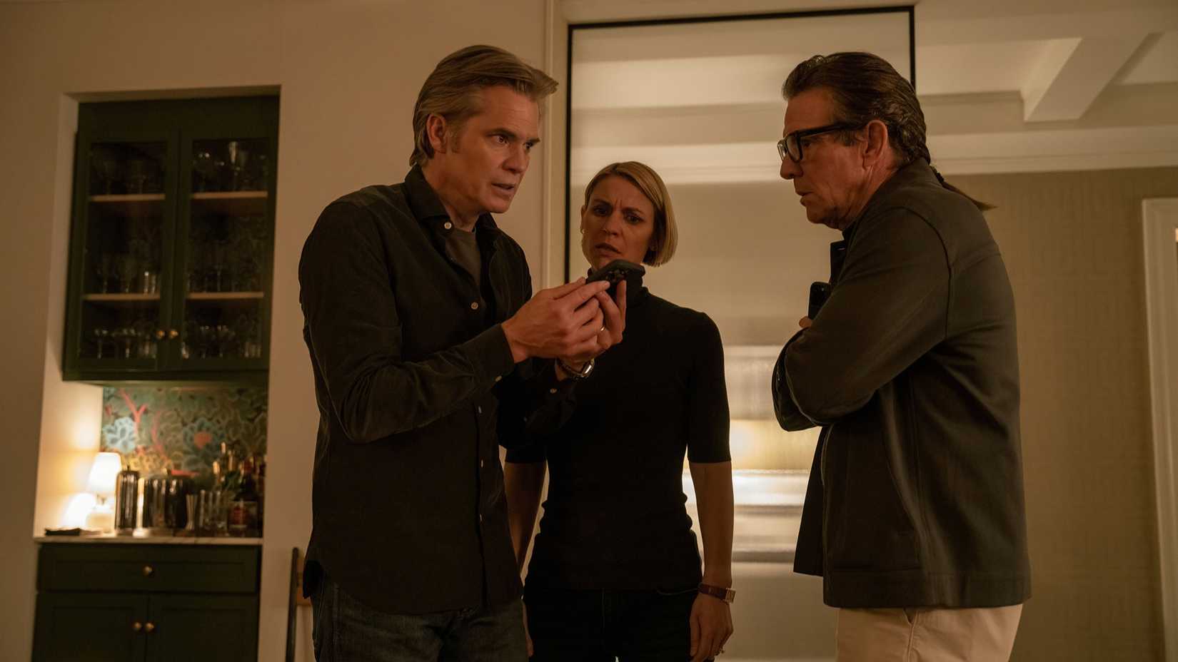 Claire, Derek, and Jeff gathered around tensely, looking at a phone, in Full Circle.