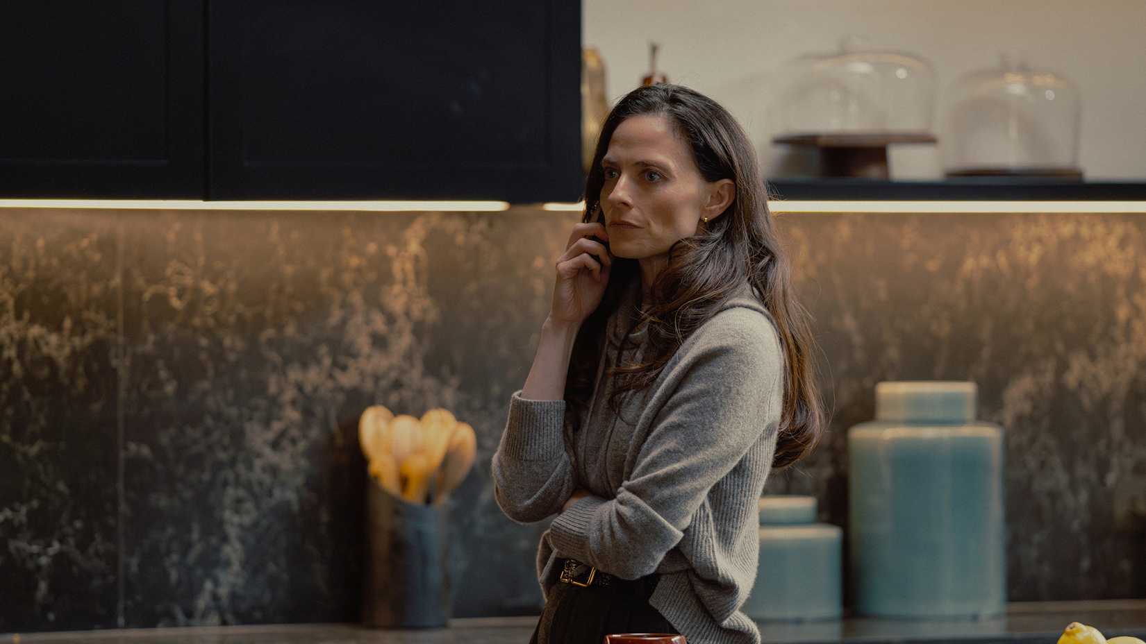 Bella Harrigan standing in a kitchen while talking on the phone in MobLand.