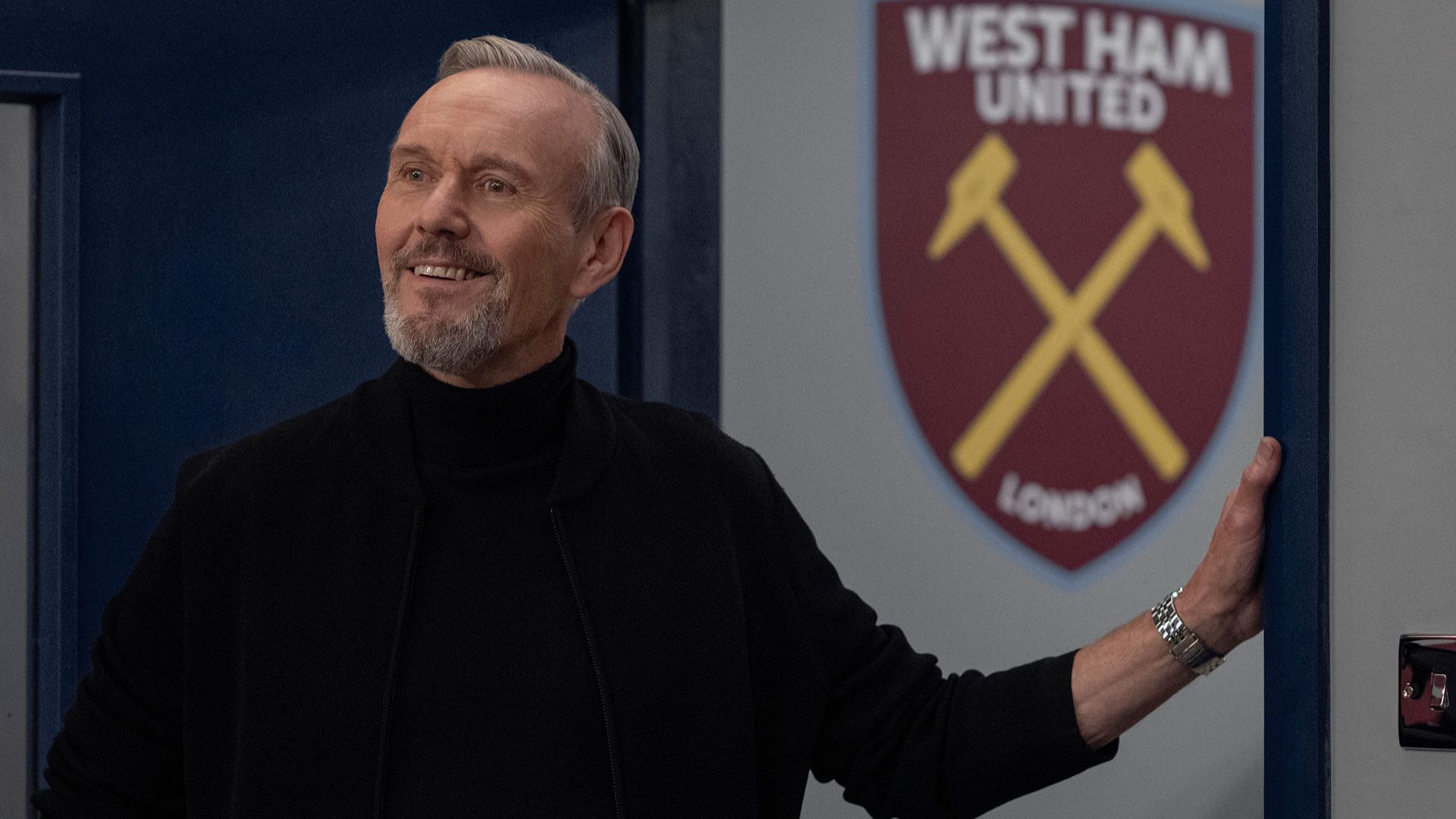 Anthony Head as Rupert at the West Ham grounds, with his hand resting on a door frame, in Ted Lasso.
